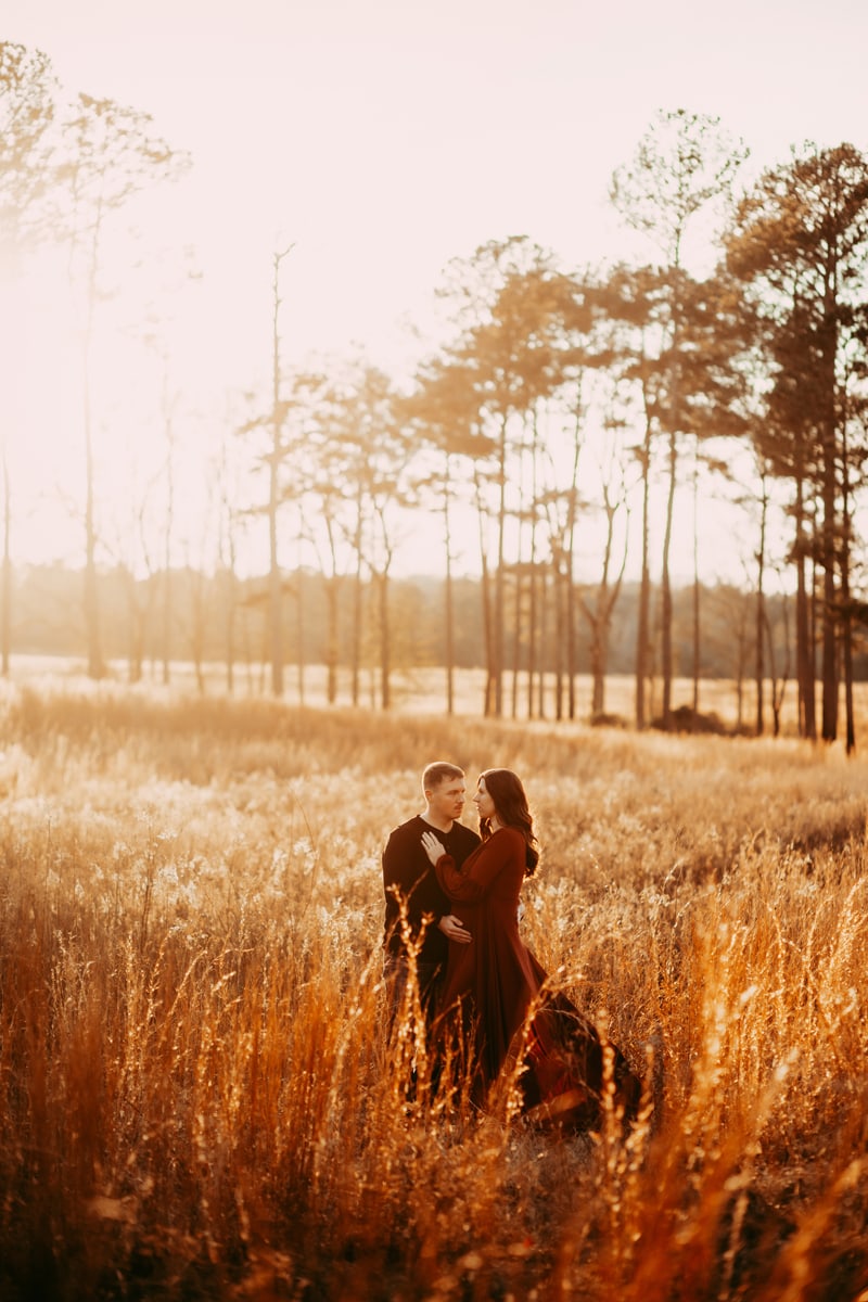 golden hour maternity - couple at a distance in a golden grassy field